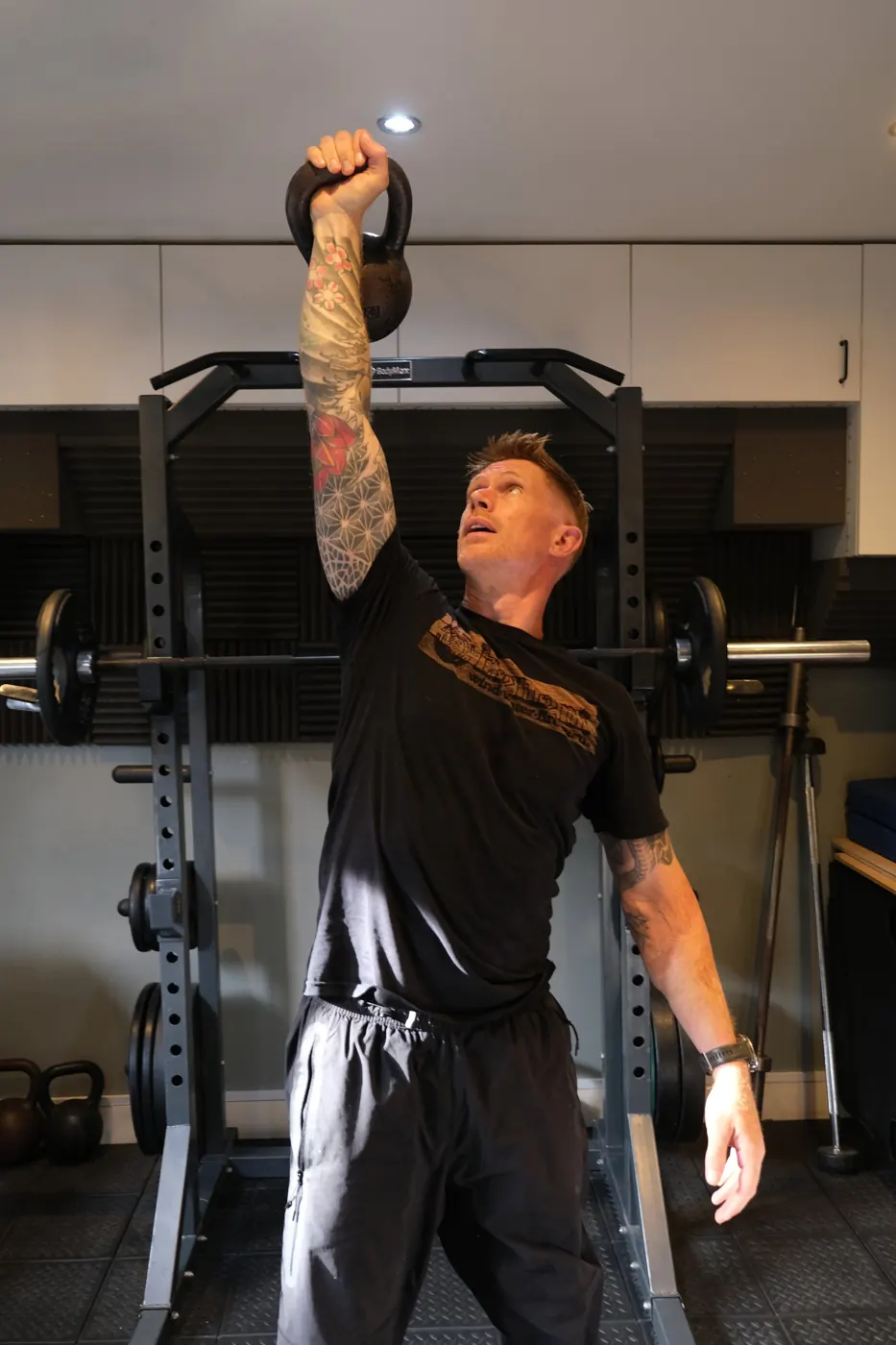 Mack Parnell pressing a kettlebell overhead in the gym